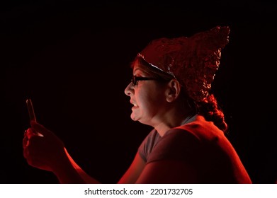 Paranoid Caucasian Woman Using Smartphone Wearing Tinfoil Hat. Conspiracy Theory. 