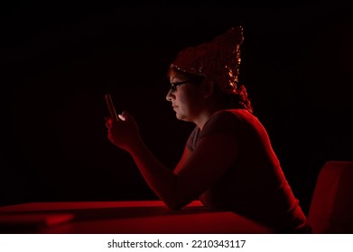 Paranoid Caucasian Woman Using Smartphone Wearing Tinfoil Hat. Conspiracy Theory. 