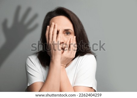 Paranoid individual. Scared woman having delusion as hand reaching for her on grey background