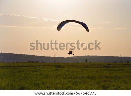 paraplan flying over a field at sunset