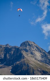 Paraplaners In Tandem Gliding In Blue Sky With View On Alpine Mountains On Paraplane