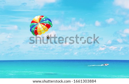 Parasailing above the ocean at tropical islands. Copy space, holiday fun activities.