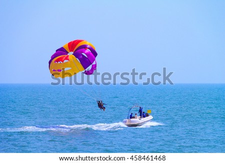 Parasailing at Candolim Beach in Goa - Indian extreme Sport. Tourists parasailing - popular entertainment for holiday travelers on Candolim Beach in Goa, India. 