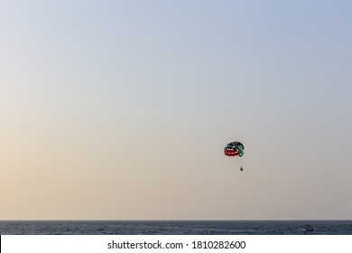 Parasailing In Dubai - Single Colorful Parasail (parachute) Tendem Wing Flying, Towed Behind A Boat Before Sunset With Orange And Blue Sky Background. Copy Space.