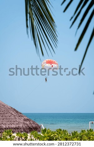 Parasailing over bright turquoise Phu Quoc sea framed by palms and tropical beach huts