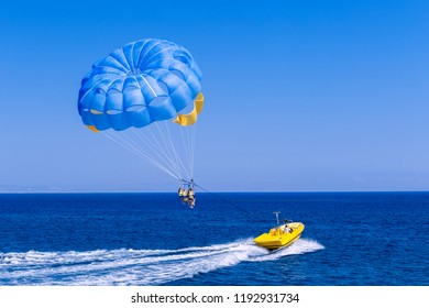 Parasailing water amusement - flying on a parachute behind a boat on a summer holiday by the sea in the resort of Cyprus.