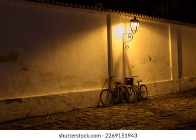 Paraty, Brazil. Bicycles on the wall under the light of old street lamps at night. Street made with stones from the colonial period. - Powered by Shutterstock