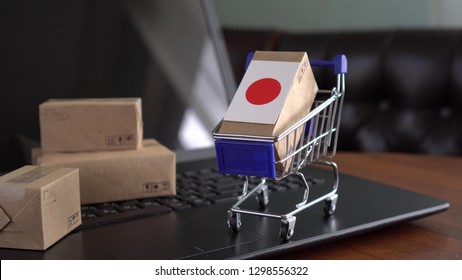 Parcel Boxes With A Flag Of Japan In A Shopping Cart On A Laptop Keyboard. Online Shopping. International E-commerce