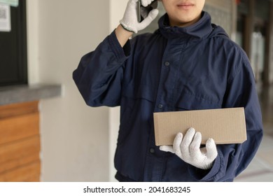 Parcel Delivery Concept The Mail Carrier Standing In Front Of The Building And Calling His Customer To Confirm The Right Address For Distributing The Parcel Post.