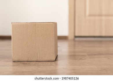 Parcel Delivery. Delivered Big Cardboard Box Lying On Floor Near Door Of Apartment, Waiting For Customer. Shipping, Modern Shopping And Courier Service Advertisement. Empty Space