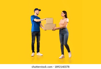Parcel Delivery. Woman Receiving Boxes From Male Courier Standing Over Yellow Studio Background. Post Package Delivering And Transportation, Couriers Service Concept. Full Length - Shutterstock ID 1892140378