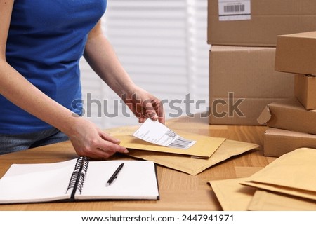 Parcel packing. Post office worker sticking barcode on bag at wooden table indoors, closeup