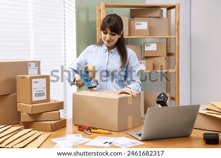 Parcel packing. Post office worker taping box at wooden table indoors