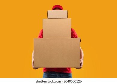 Parcels Delivery. Unrecognizable Courier Guy Holding Many Big Cardboard Boxes Delivering Packages To You Posing Standing In Studio Over Yellow Background. Postal Shipping Service Concept - Shutterstock ID 2049530126