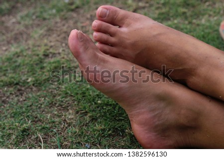 Parcially dirty feet of a young woman in the grass, after a full day walking through the park