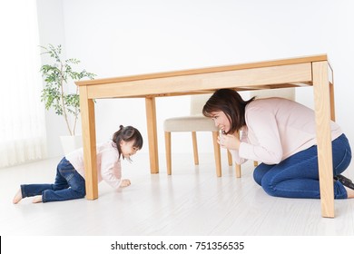 A Parent And Child Huddling Under A Table