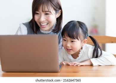 Parent and child looking at a computer - Shutterstock ID 2162647365