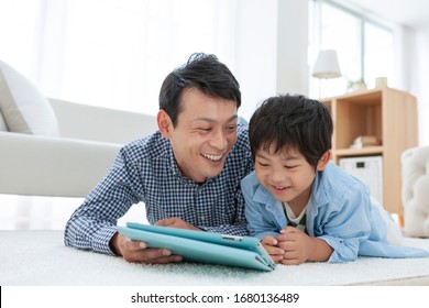 Parent And Child Looking At Tablet In Living Room