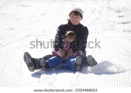 Parent and child playing on a sled
