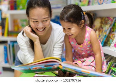 Parent And Child Reading Books Together In The Library.