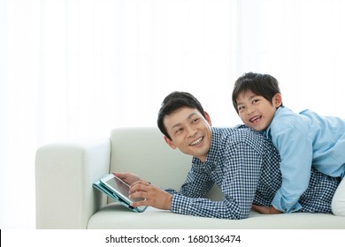 Parent And Child Watching Tablet On Sofa