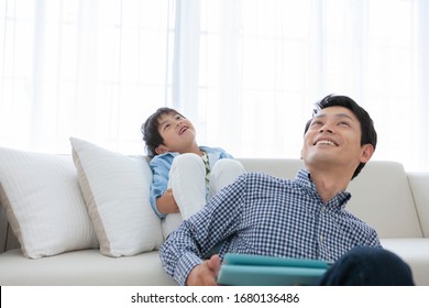 Parent And Child Watching Tablet On Sofa