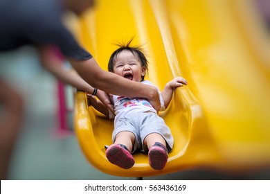 Parent hand holding Asian kids on slide in playground under sun light in summer, concept of family.