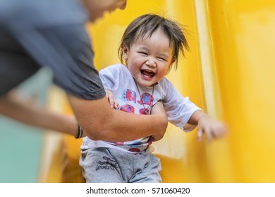 Parent hand holding Asian little baby kid on slide in playground under sun light in summer, concept of family - Powered by Shutterstock