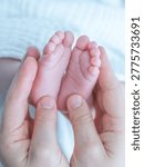 Parent hands gently cradling tiny baby feet, showing tenderness and new life
