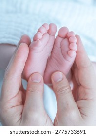 Parent hands gently cradling tiny baby feet, showing tenderness and new life
