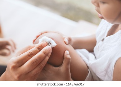 Parent Helping Her Child Perform First Aid Knee Injury After She Has Been An Accident