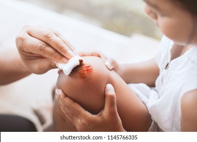 Parent Helping Her Child Perform First Aid Knee Injury After She Has Been An Accident