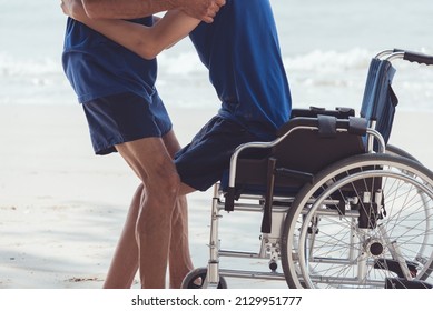 Parent helping helping the young man to stand up from the wheelchair, Caring for people with disabilities in their daily lives by parents, caregivers or volunteers and mental health concept.