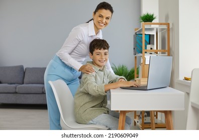 Parent Helps Child Do Homework Or Log Into Online Class. School Teacher Helping Kid Learn ICT Basics. Mother And Son Using Laptop Computer At Home. Portrait Of Happy Young Woman And Smart Student