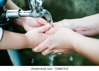 Parent Is Holding Hand And Washing His Baby's Hand./Closeup Photo Of Woman Washing Hands In A City Fountain