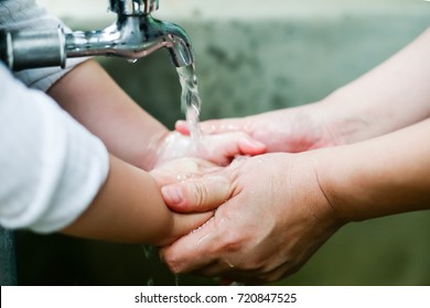 Parent Is Holding Hand And Washing His Baby's Hand./Closeup Photo Of Woman Washing Hands In A City Fountain