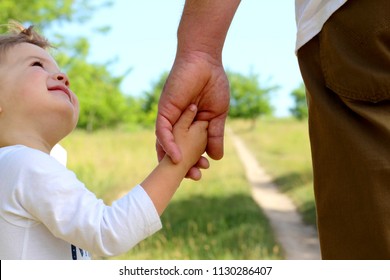 A Parent Holds The Hand Of A Small Child