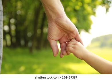 A Parent Holds The Hand Of A Small Child