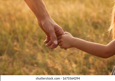 der Elternteil die Hand eines kleinen Kindes hält
