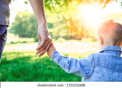parent holds the hand of a small child and walk