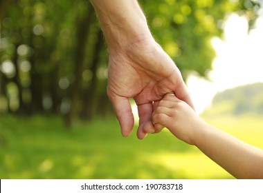 a parent holds the hand of a small child