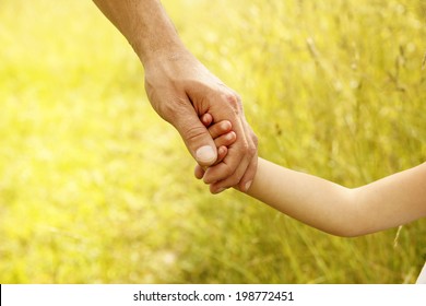 a parent holds the hand of a small child 