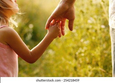 a parent holds the hand of a small child - Powered by Shutterstock