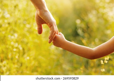 ein Elternteil die Hand eines kleinen Kindes hält