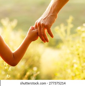 ein Elternteil die Hand eines kleinen Kindes hält