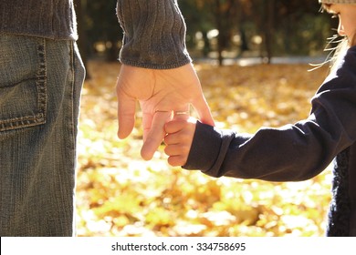 a the parent holds the hand of a small child