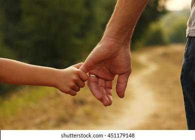 The Parent Holds The Hand Of A Small Child