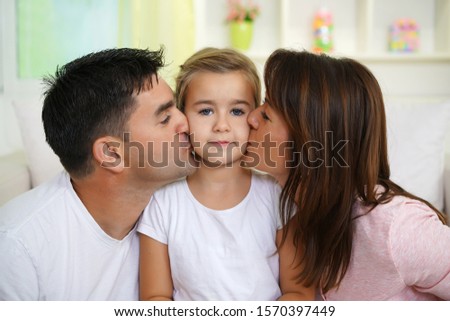   Parent kissing daughter , family indoors                             