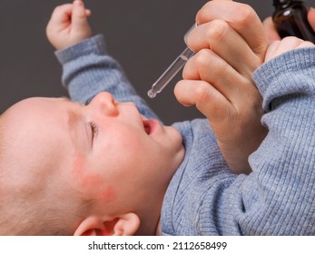 Parent Pipetting Cbd Oil Into Baby's Mouth.allergy Dermatitis On The Head Of An Infant