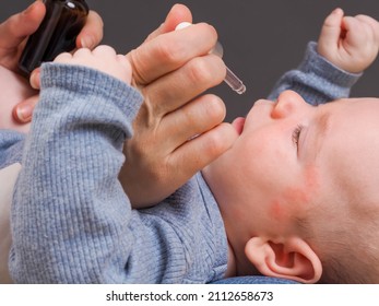 Parent Pipetting Cbd Oil Into Baby's Mouth.allergy Dermatitis On The Head Of An Infant